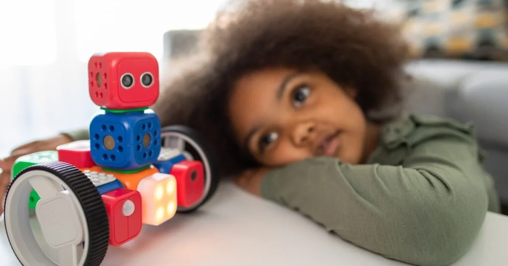boy lying on bed playing with red and blue toy truck